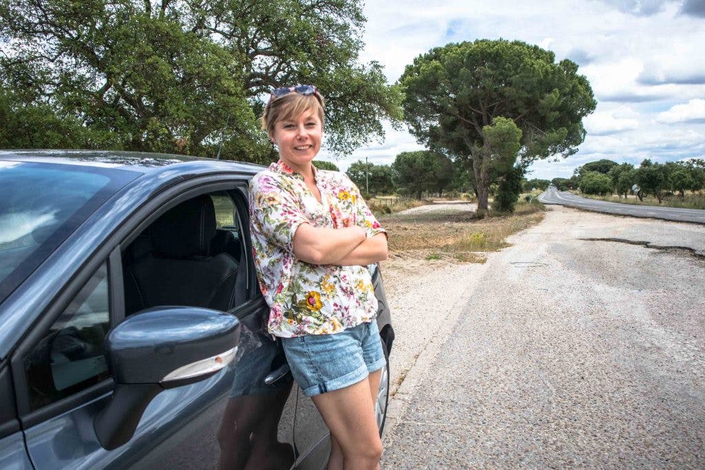 a girl standing next to a car on an anlentejo road