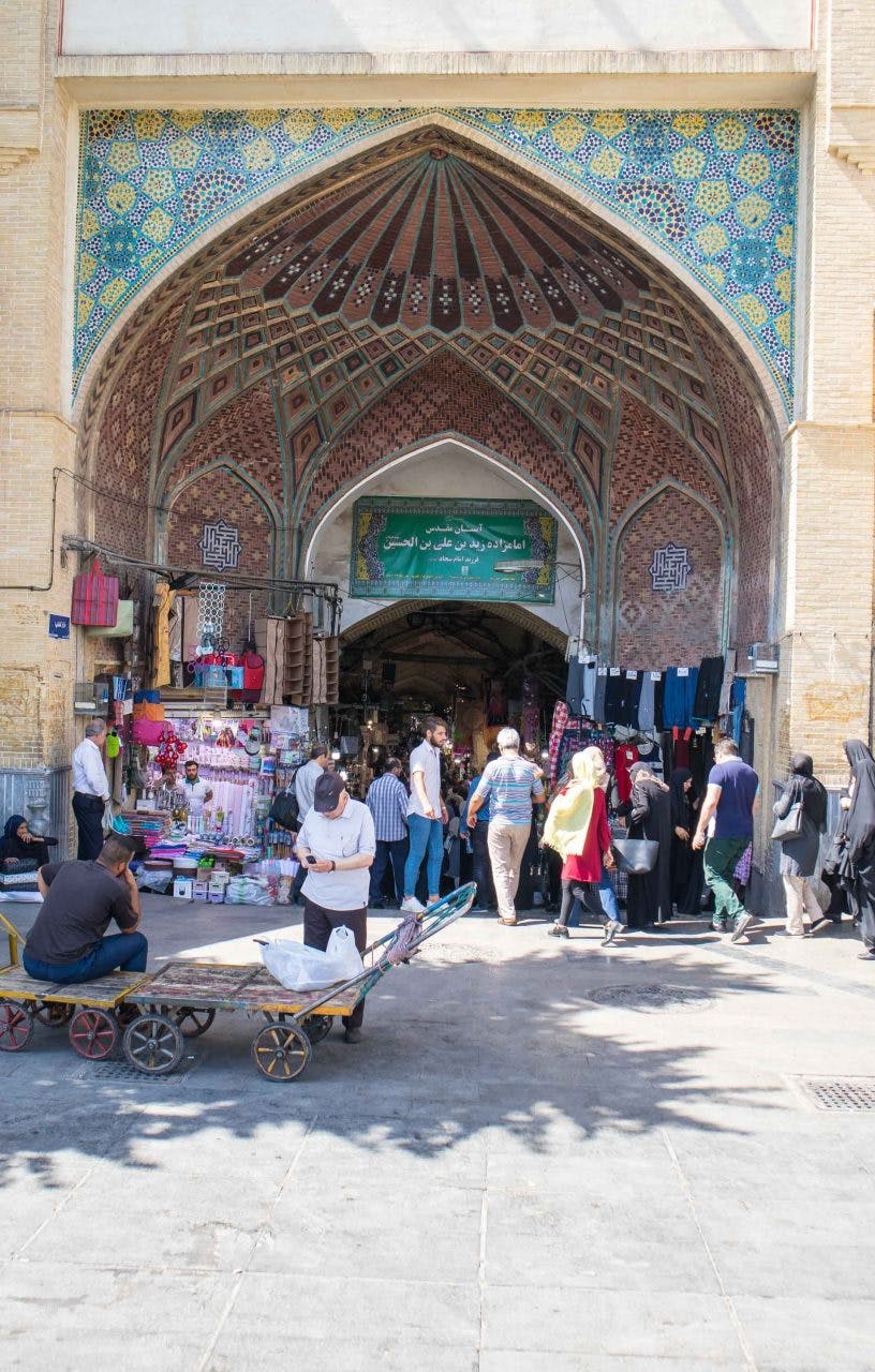 market in teheran with crowds of people in front of mosque 