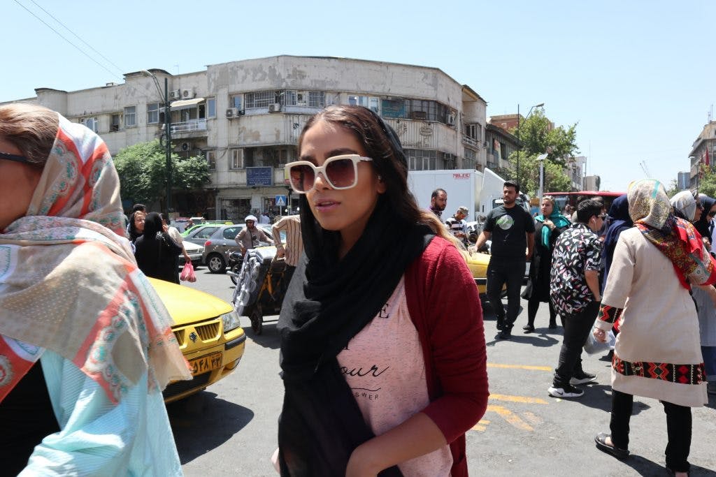 mloda iranka w slonecznych okularach na zatloczonej ulicy w teheranie