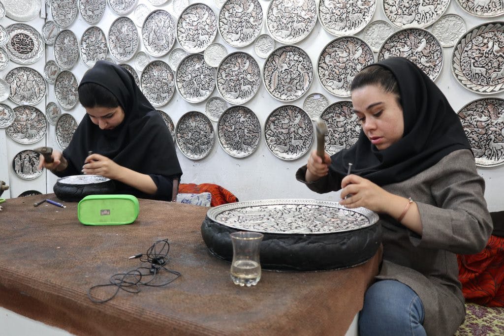 dwie młode iranki pracują nad rzeźbami ze srebra w warsztacie w Esfahan