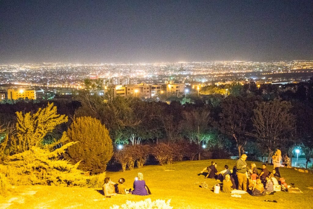 Ludzie siedzą w nocy na górze Soffeh w Esfahan w Iranie. 