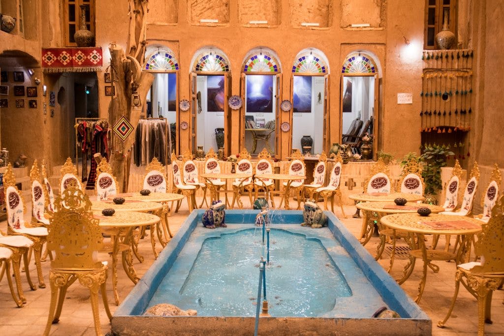 the inside of the tourist library in yazd: tables with chairs and a pool
