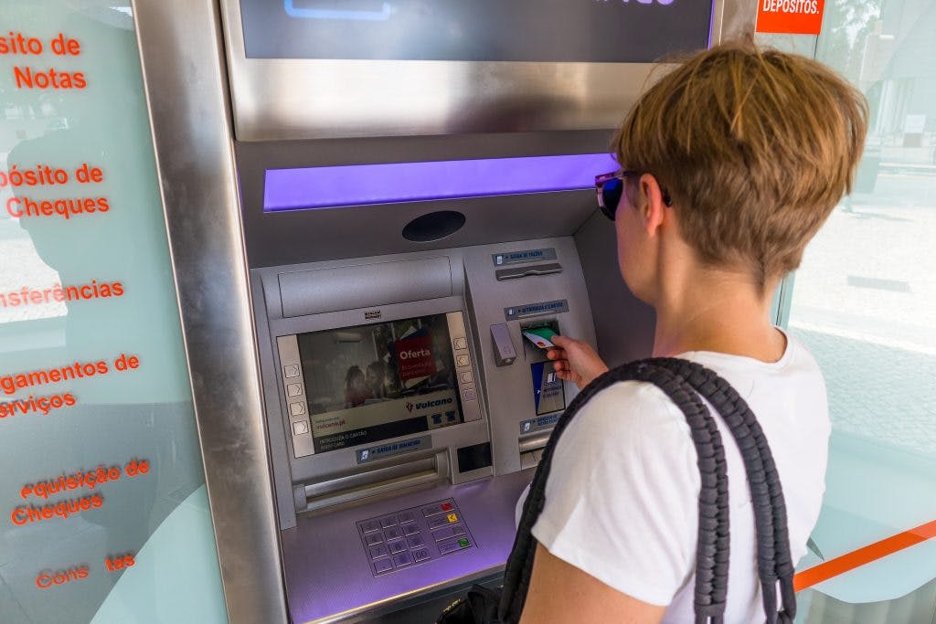 dziewczyna wyciąga gotówkę z bankomatu kartą monese w Portugalii