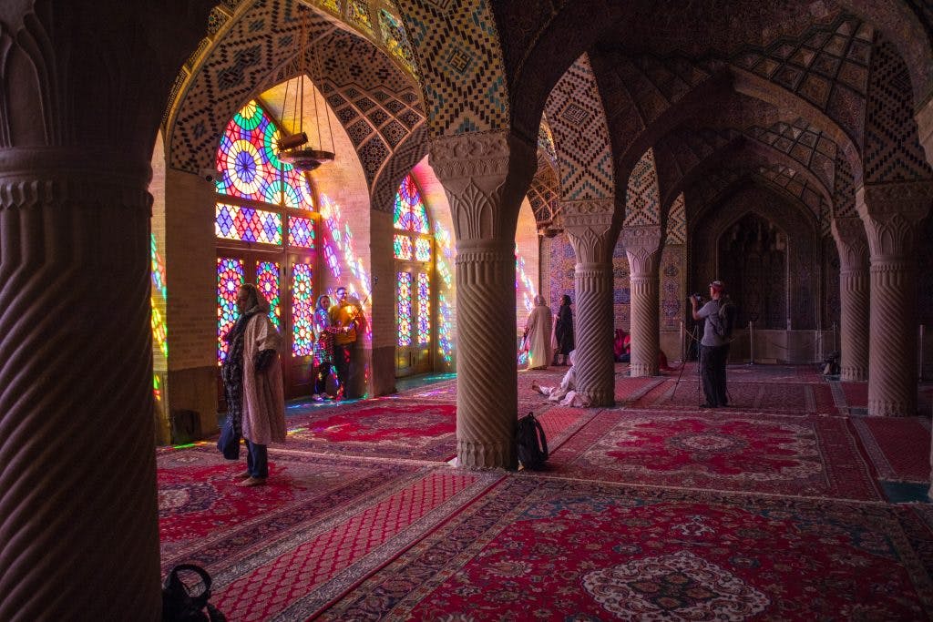 turyści w różowym meczecie przechadzają się po pomieszczeniu i robią zdjęcia