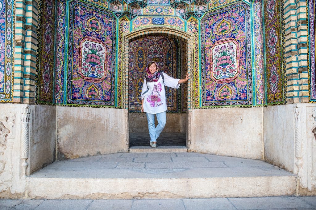 dziewczyna stoi w rozowych drzwiach w meczecie w shiraz, w iranie.