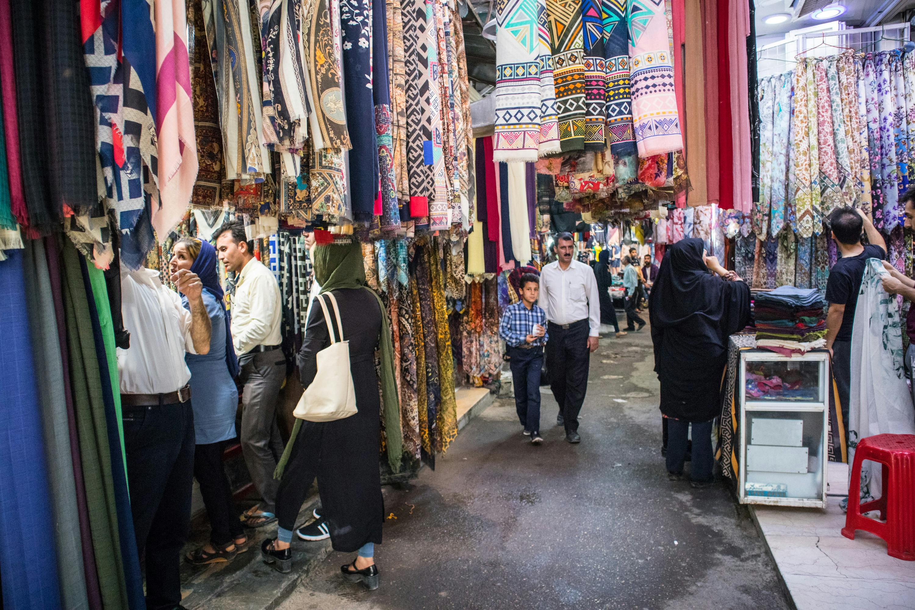 syn z ojcem przechadzają się po Vakil Bazar w Shiraz, w Iranie. Z sufitu zwisają chusty i dywany. 