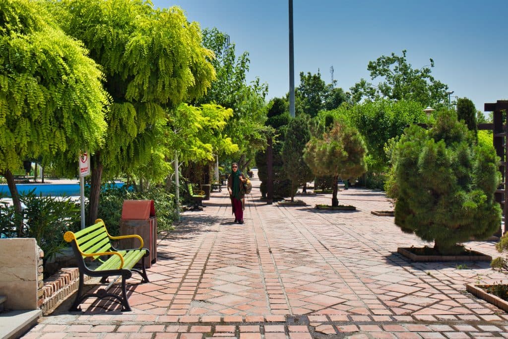 a woman walks through a park in iran