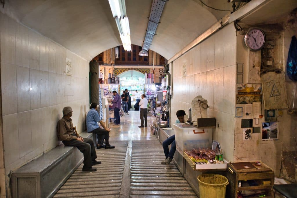 men sitting and watching people in grand bazaar teheran