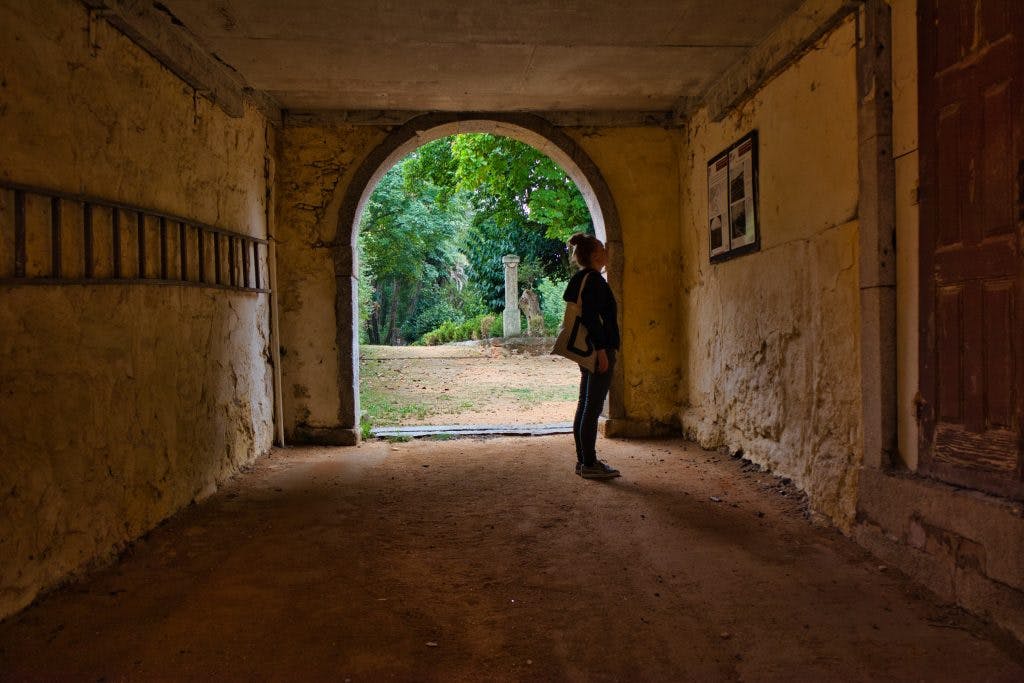 Magda Horanin stands in an old building reading the information board