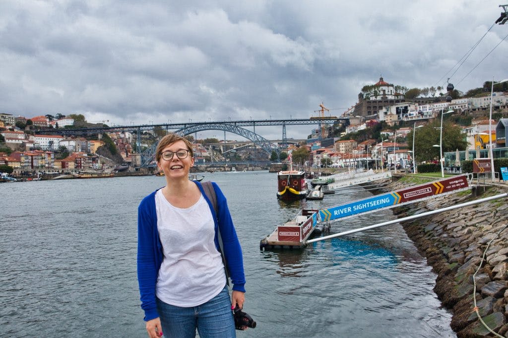 joanna horanin stands at the river bank in porto, portugal on a very cloudy and rainy day