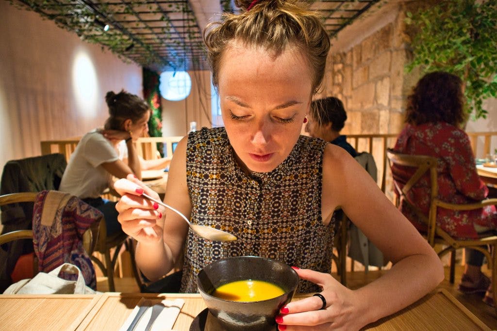 a girl eating a soup in a cosy restaurant