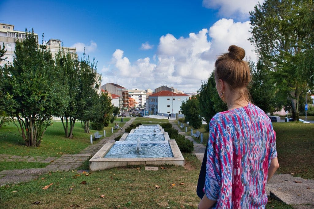 a girl stands on a hill and looks down on vila nova de gaia in porto portugal