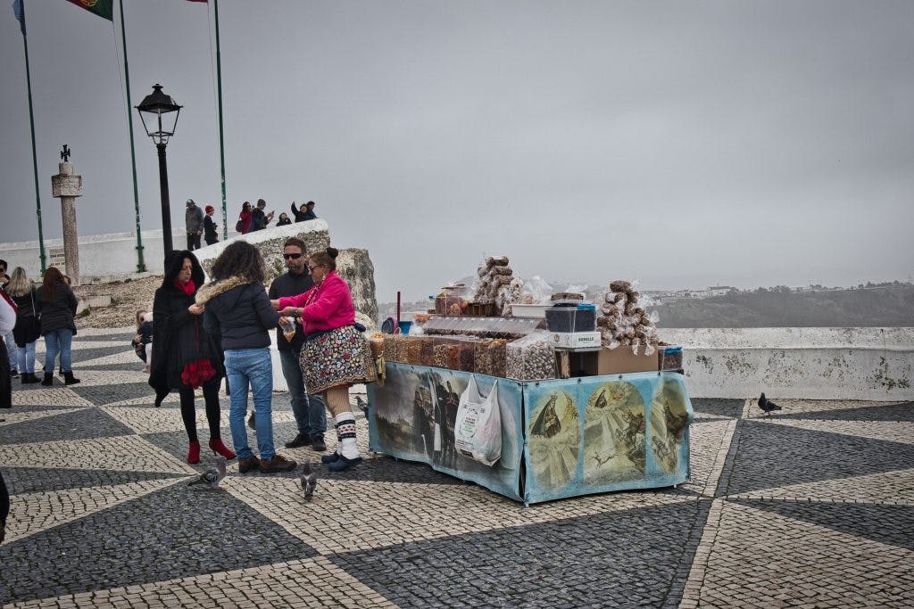 an older lady dressed in seven skirts selling nuts in nazare