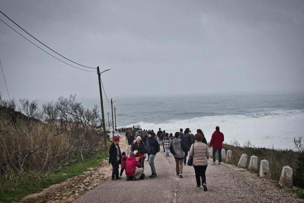 crowds of people walking to the lighthouse in nazare to watch the waves
