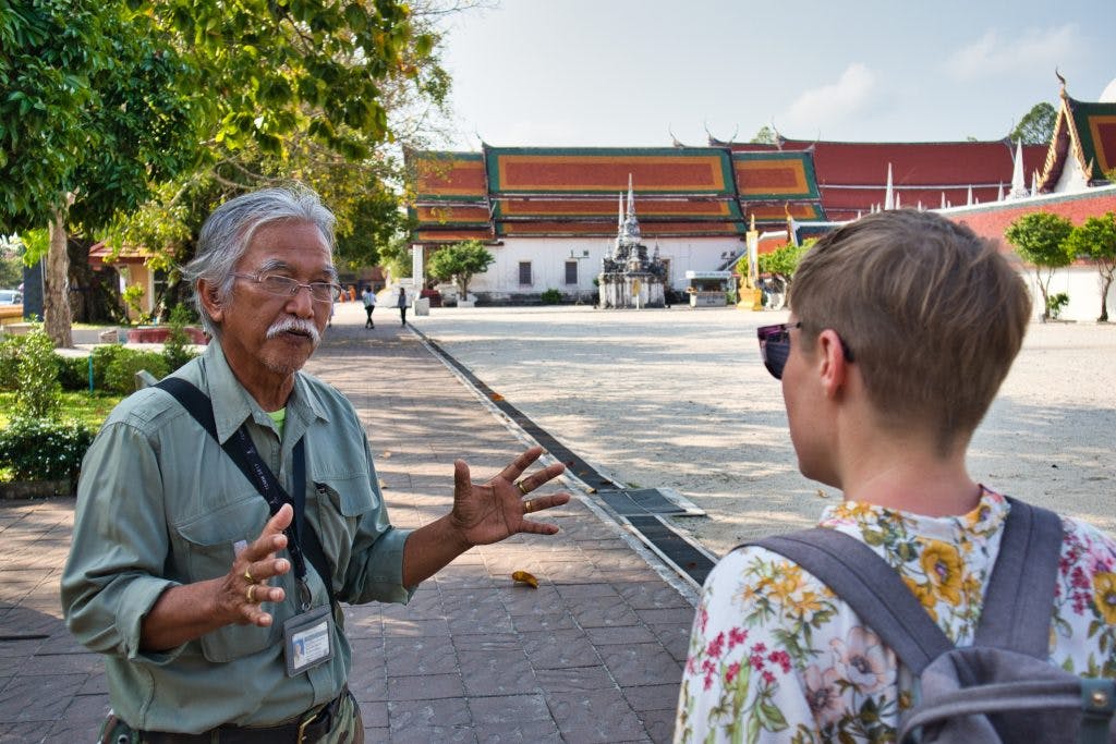 a Thai man and a foreign woman talking in front of a temple in Thailand