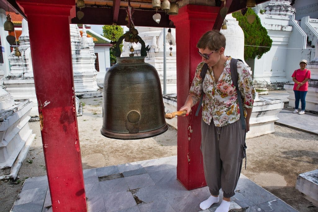 a woman ringing a buddhist bell at the temple in nakhon si thammarat 