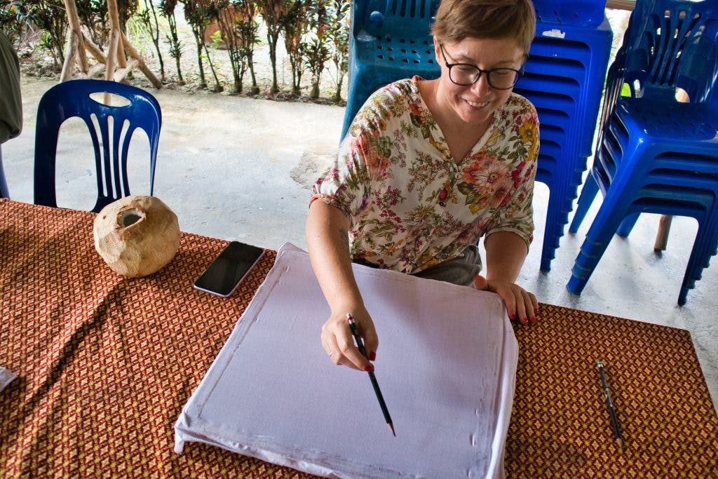 kobieta rysuje ołówkiem po płótnie w promlok community nakhon si thammarat 