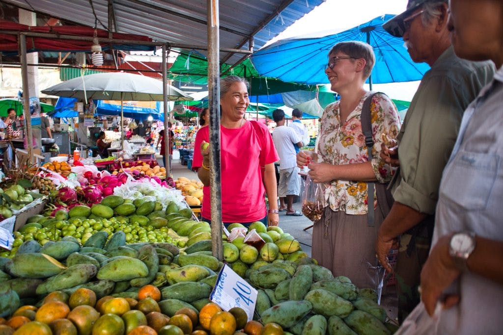 a woman in a flowery shirt talking to a Thai lady at a local market in Promlok.