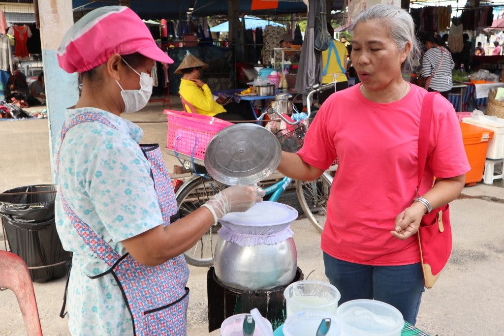 two Thai women at a local market talking about Thai desserts