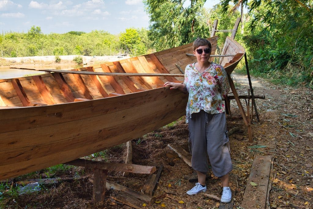 a tourist woman checks out a long tail boat in a workshop in koh klang thailand. 