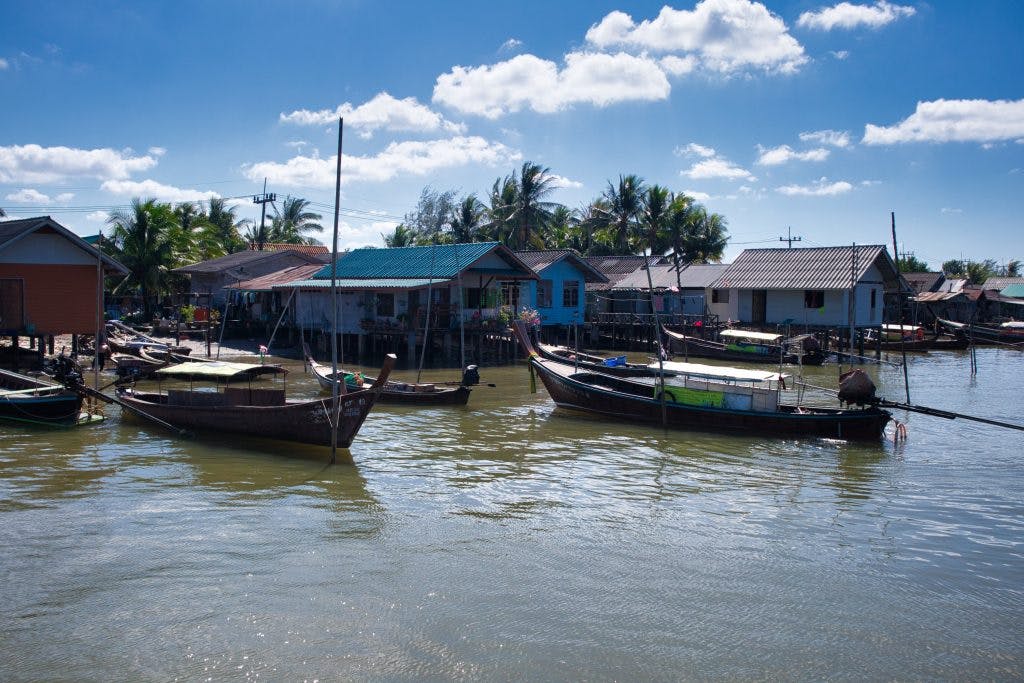 boats standing at huts on stills on a river in koh klang, thailand. 