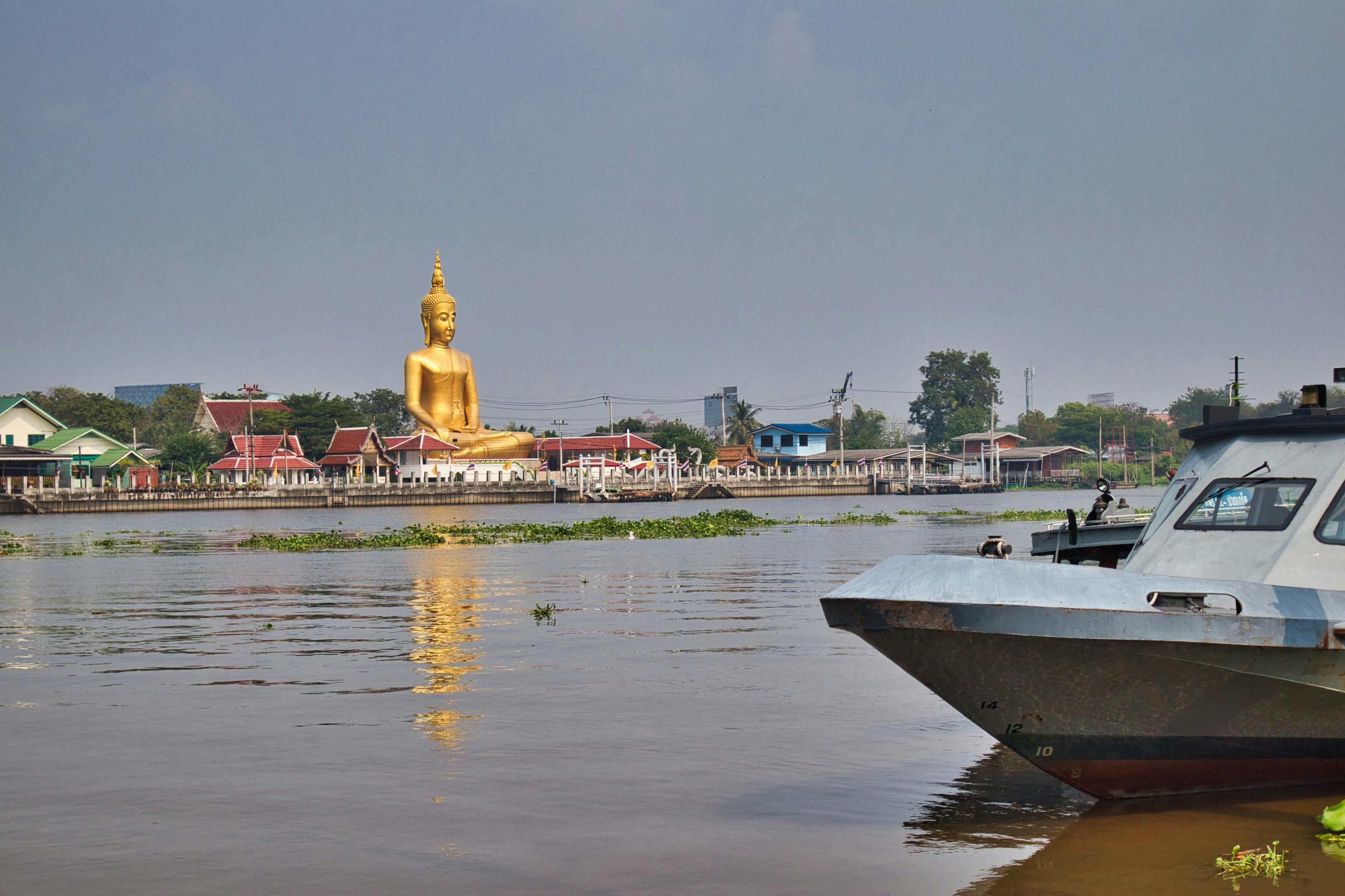 a golden buddha statue over a river in bangkok, koh kret, thailand