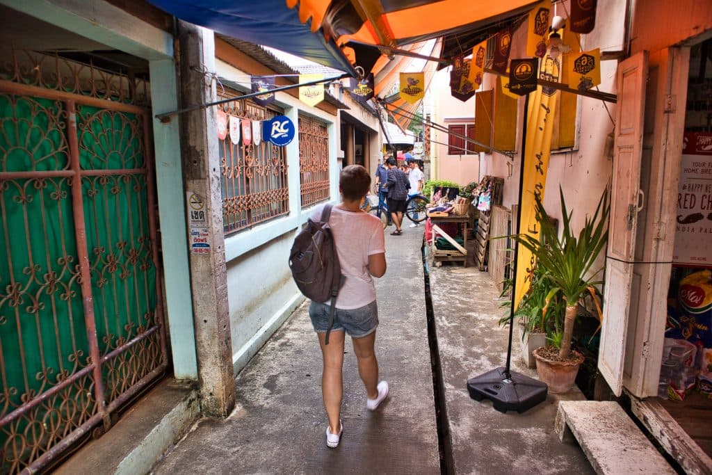a girl walks through a village with a backpack on the Koh kret island
