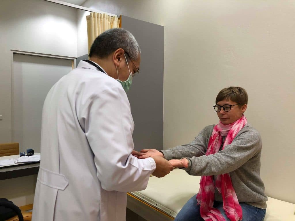 a woman at a health exam at ram hospital in chiang mai. the doctor looks at her hands.