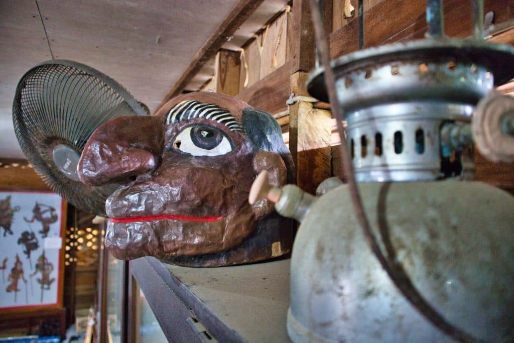 a mask of a man sits on a shelf in nakhon si thammarat puppet museum