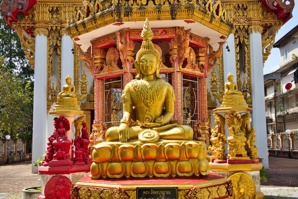 a golden buddha sits at a entrance to the temple in nakhon si thammarat in thailand
