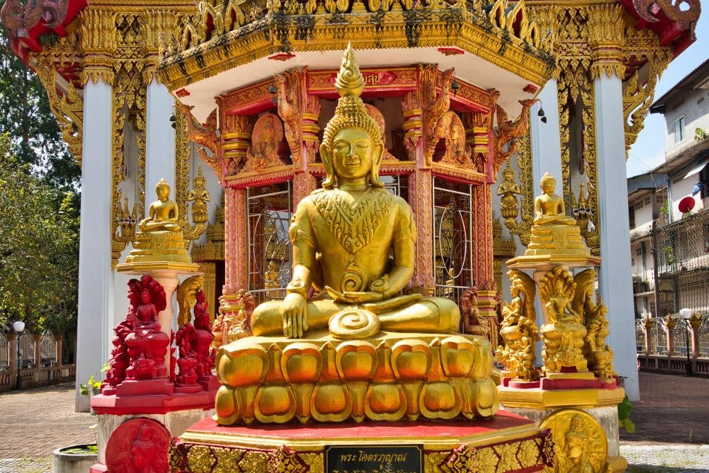 a golden buddha sits at a entrance to the temple in nakhon si thammarat in thailand 