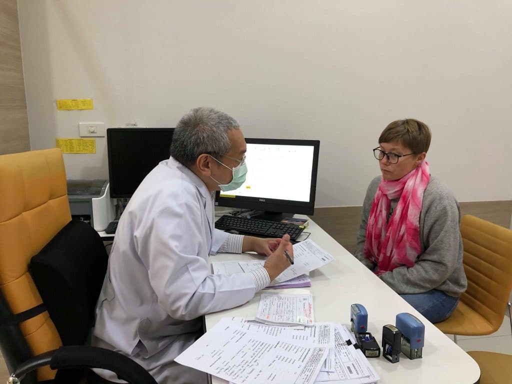 a woman is talking to a Thai doctor about her results at chiang mai ram hospital. she looks worried as he explains the result.