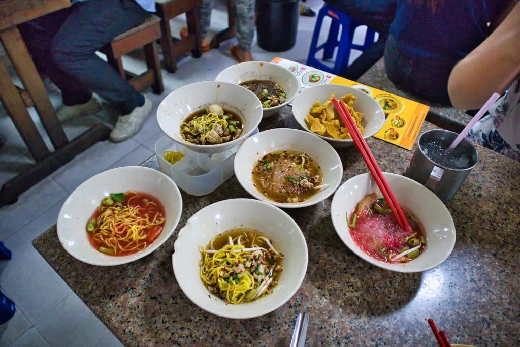 lokalne jedzenie w Bangkoku - małe talerze boat noodles w różnych kolorach na stole.
