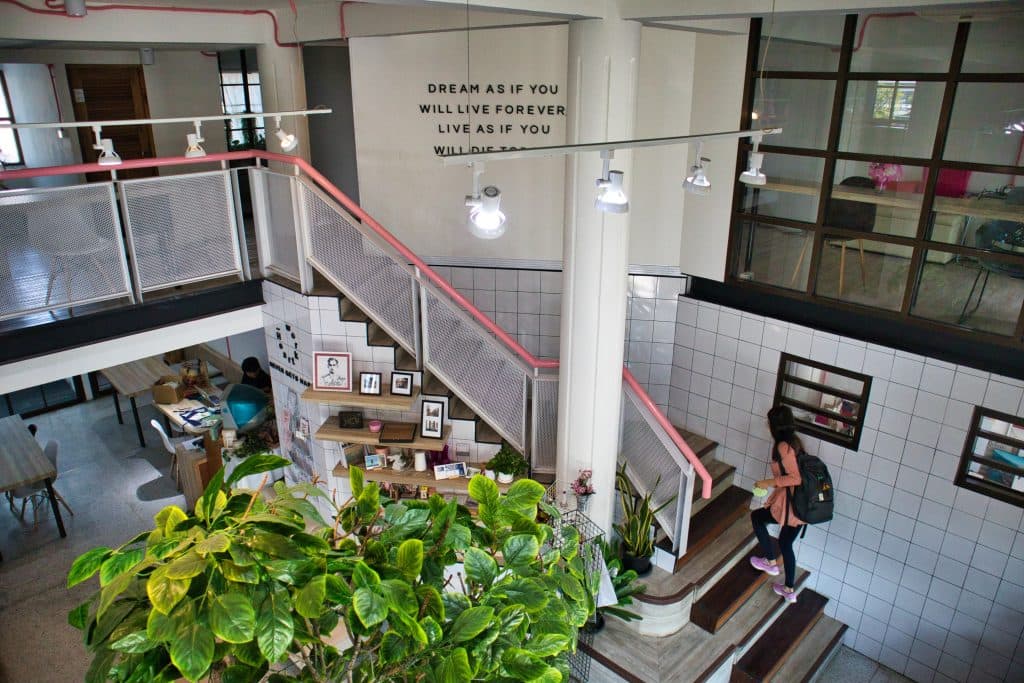 A woman in a pink top with a backpack is walking up the stairs at Heartowrk, Chiang Mai.