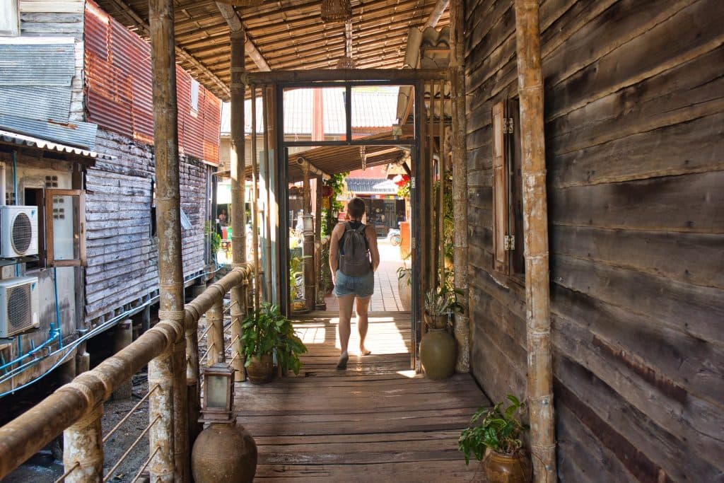 a woman walking on a wooden bridge in the old town in koh lanta.