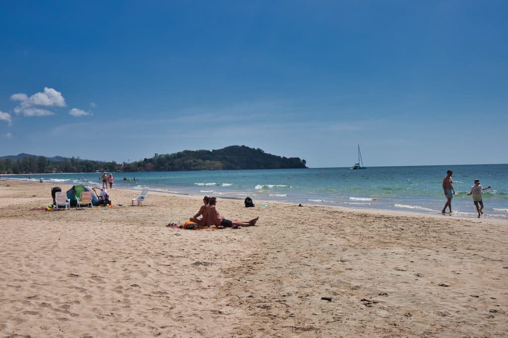 people sitting on the sand on koh lanta beach, thailand.