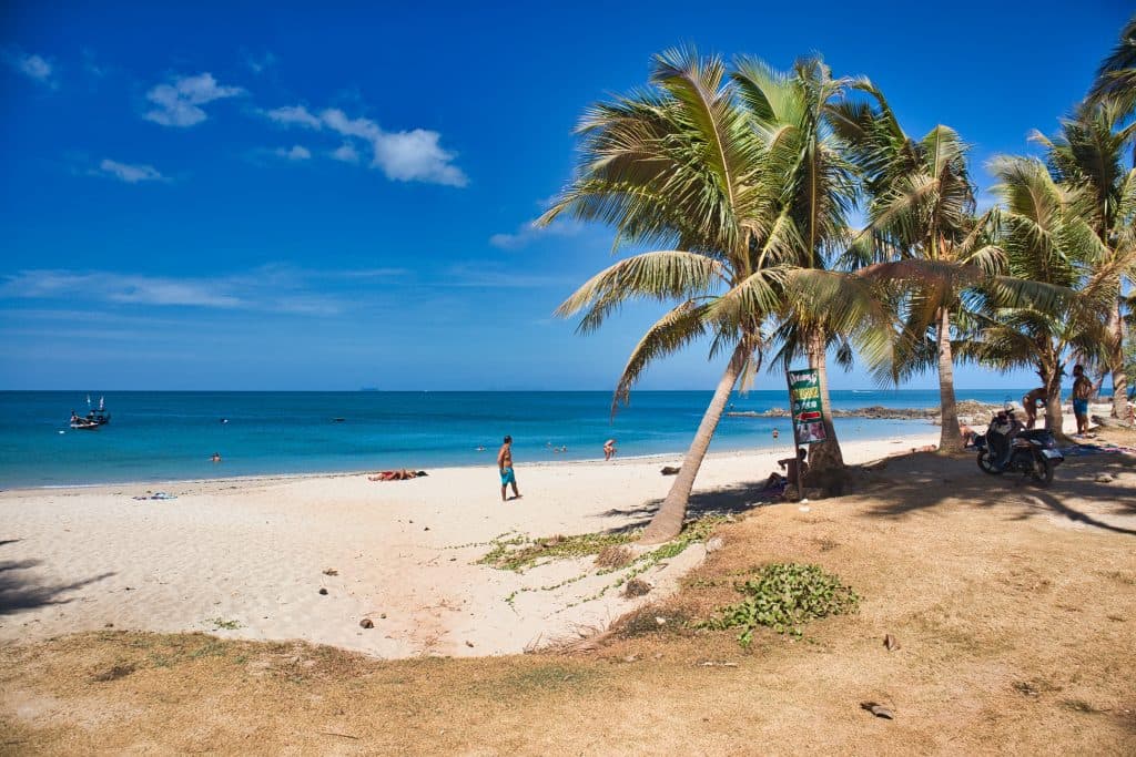 a man in blue shorts standing in the middle of the secret beach on koh lanta, thailand.