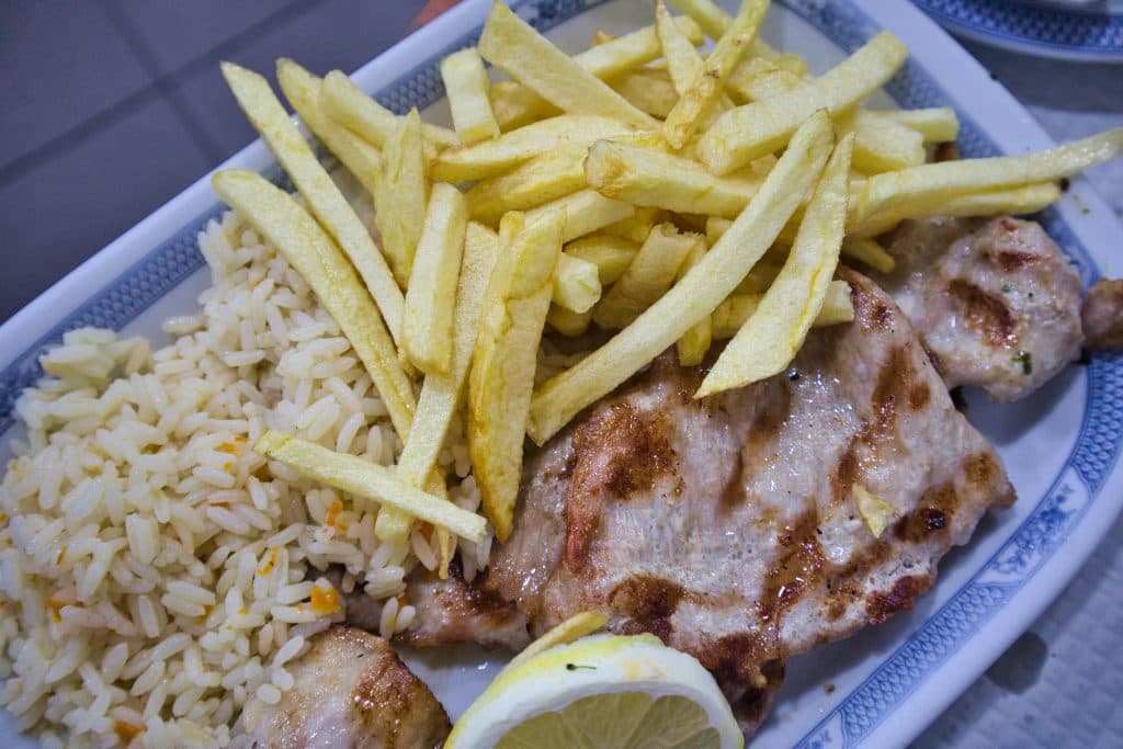 a steak with fries on a plate in a tasca i lisbon