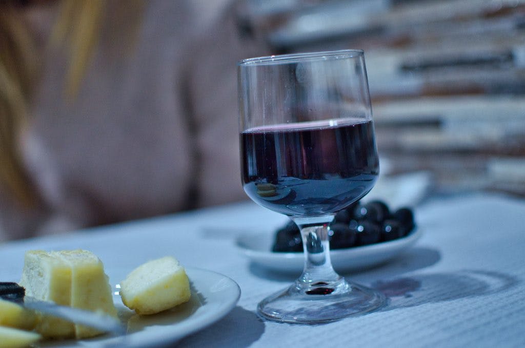 Kieliszek czerwonego wina i talerz sera na stole w tasce w Lizbonie. 