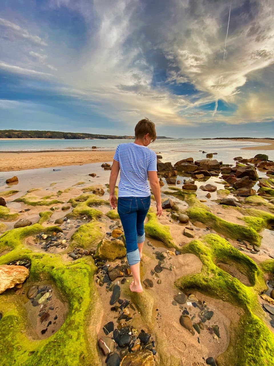 A woman walking on the beach in vila nova de milfontes.