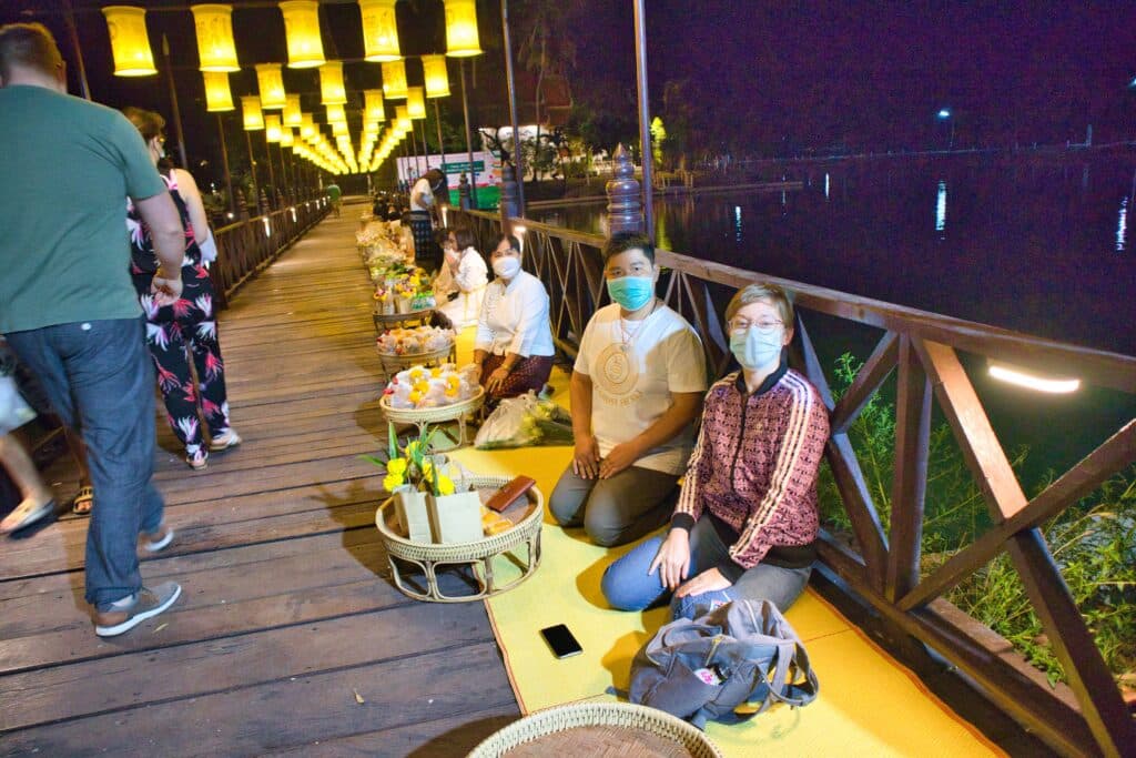 Kobieta i mężczyzna w Tajlandii czekają na złożenie darów mnichom.