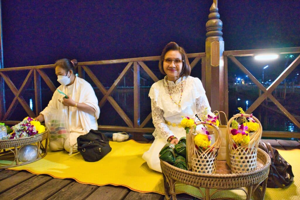 Tajska kobieta, odświętnie ubrana, czeka na mnichów.