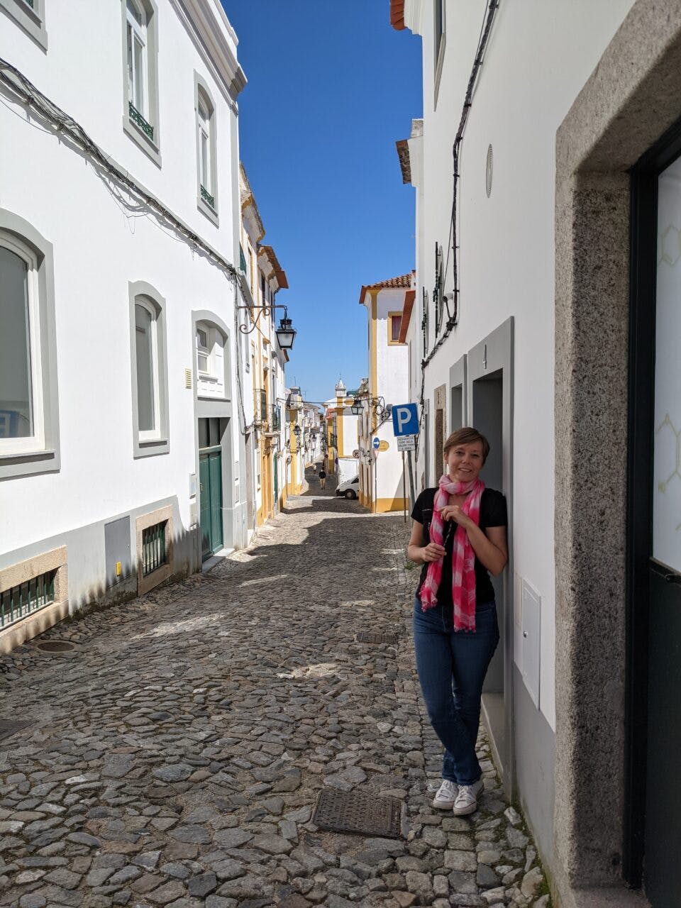 Dziewczyna stoi na ulicy w Evorze, w Portugalii. Opiera się o budynek.