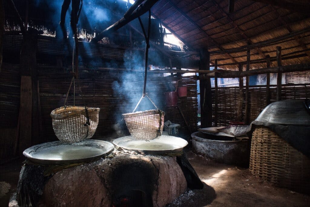 Baskets of salt hang above a fuming hole in a bamboo hut. 
