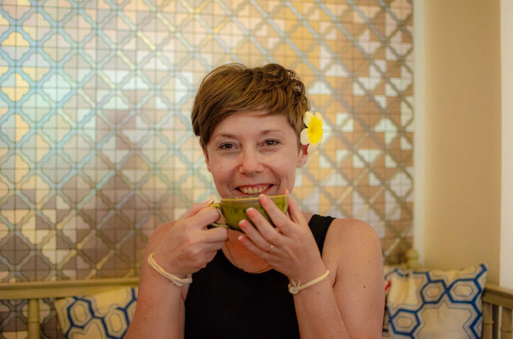 A woman drinking tea and smiling at the camera at Absolute Sanctuary, Koh Samui.