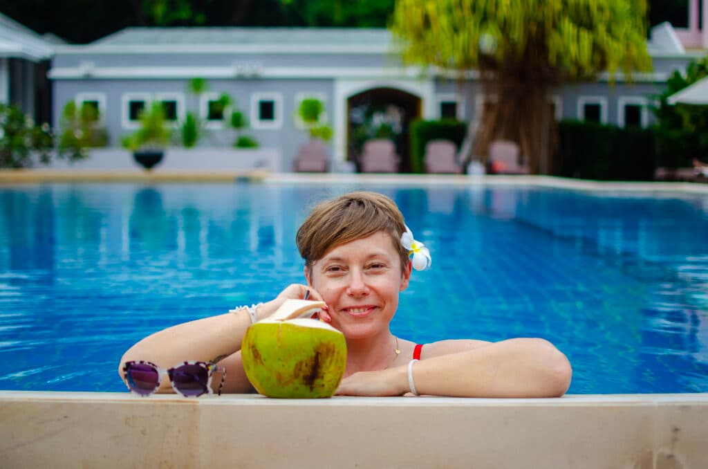 A girl with a coconut in a swimming pool.