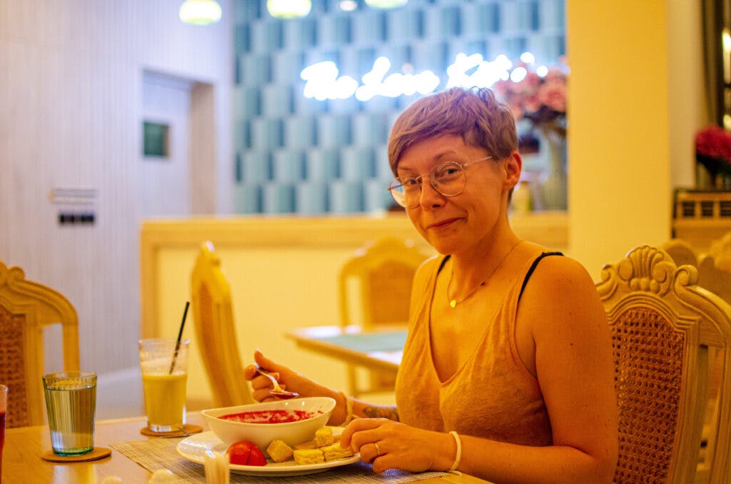 A woman sitting and smiling while she eats at absolute sanctuary, koh samui.