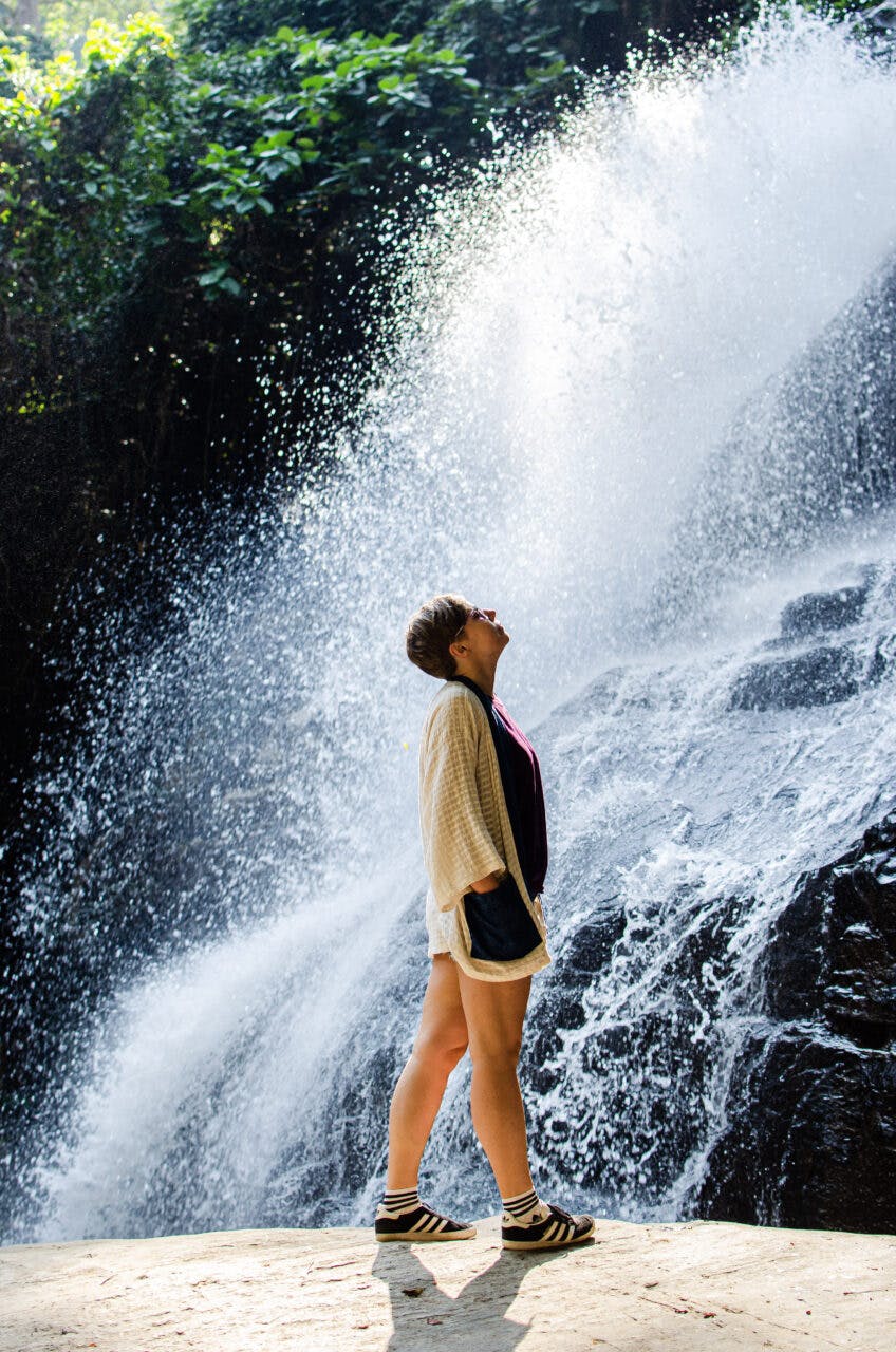 Dziewczyna stoi przy wodospadzie niedaleko Chiang Mai. 