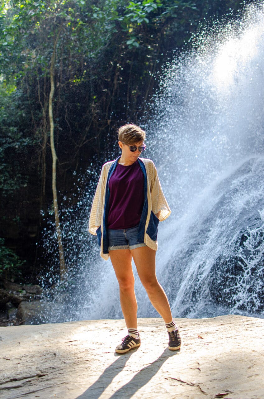 Dziewczyna stoi na tle wodospadu niedaleko Chiang Mai. 