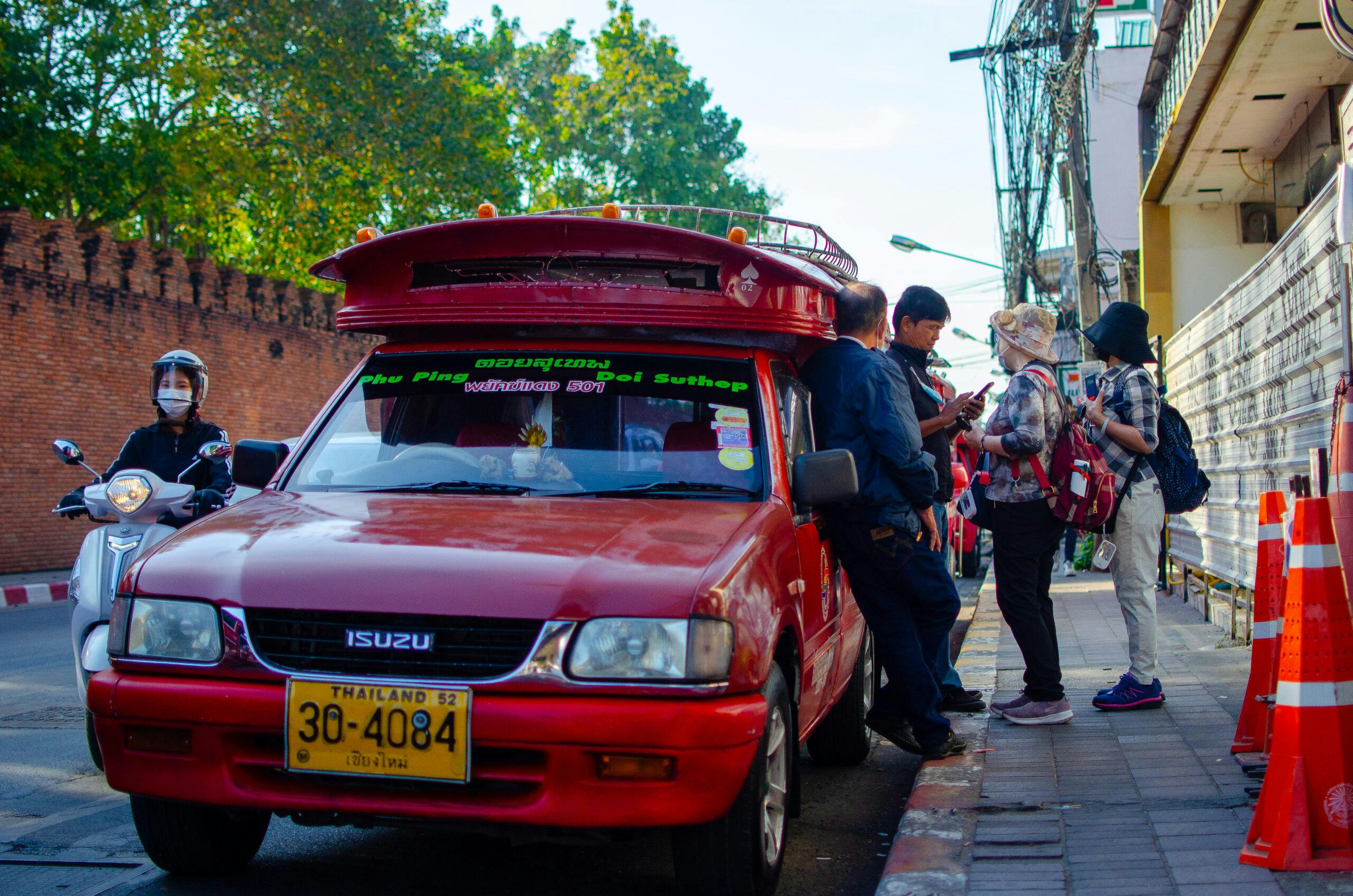 People catching a red taxi in chiang mai.